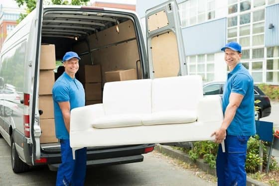 Two men carrying a white sofa